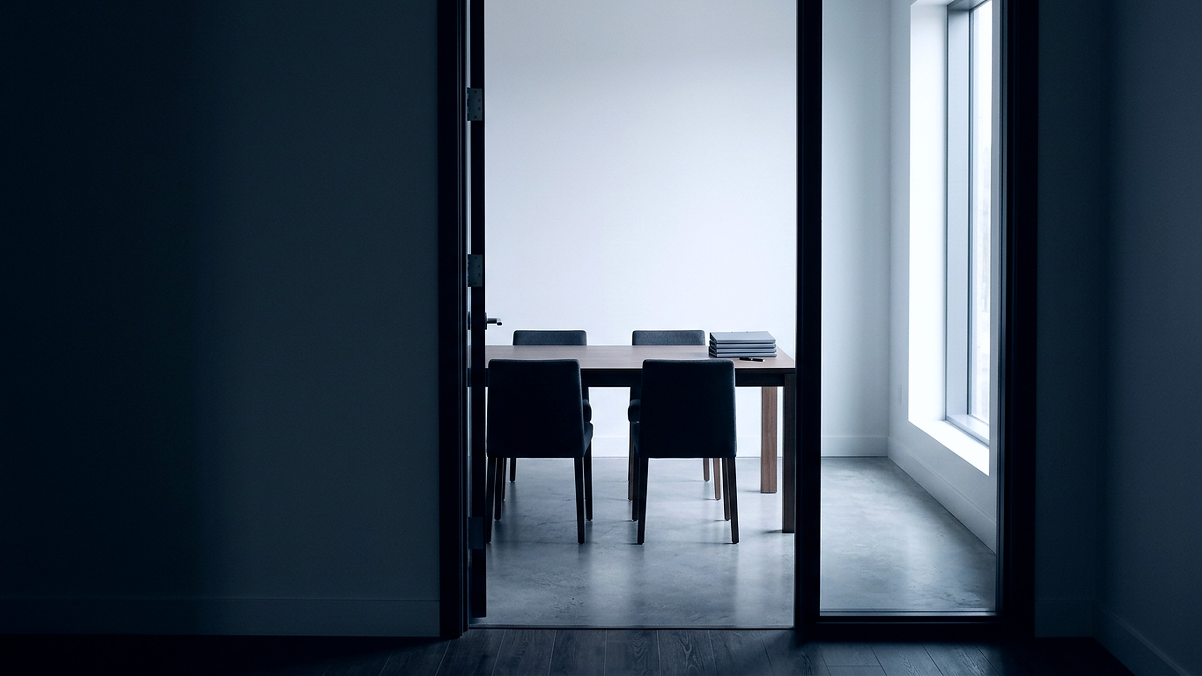 An empty, well-lit meeting room seen from the doorway, chairs squared to a plain table.